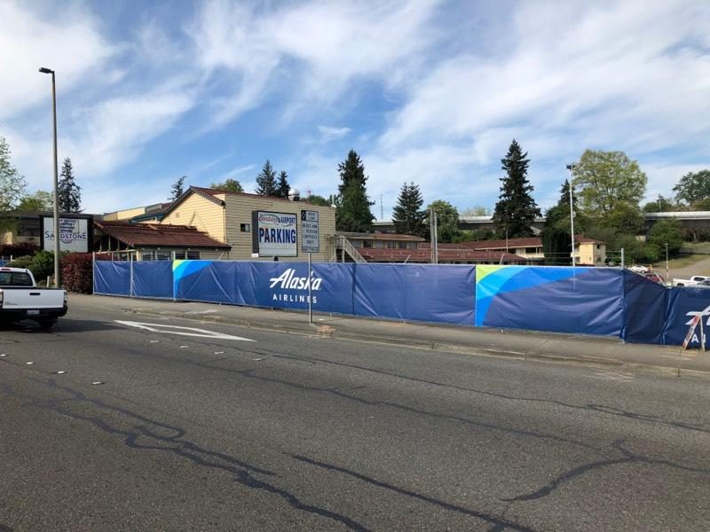 Long run of Alaska Airlines printed construction fence screen at a roadside site