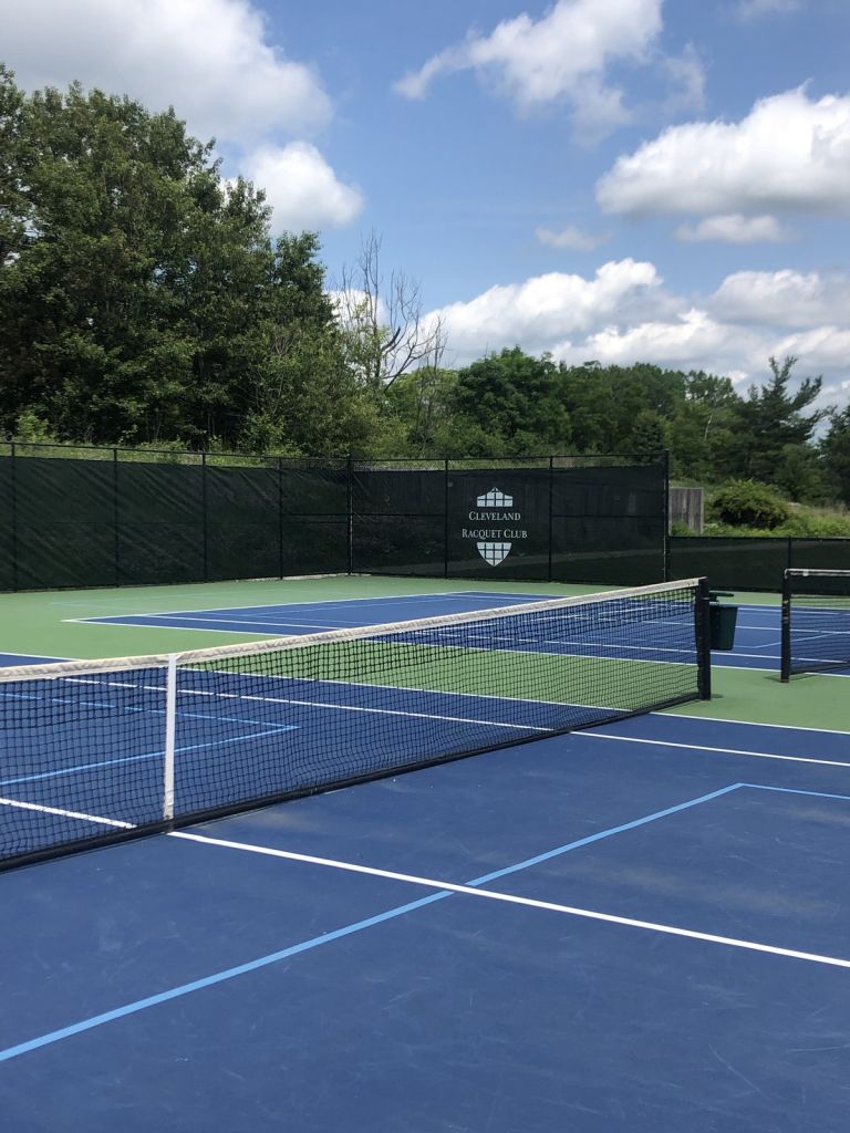 Black tennis court windscreen with white Cleveland Racquet Club logo