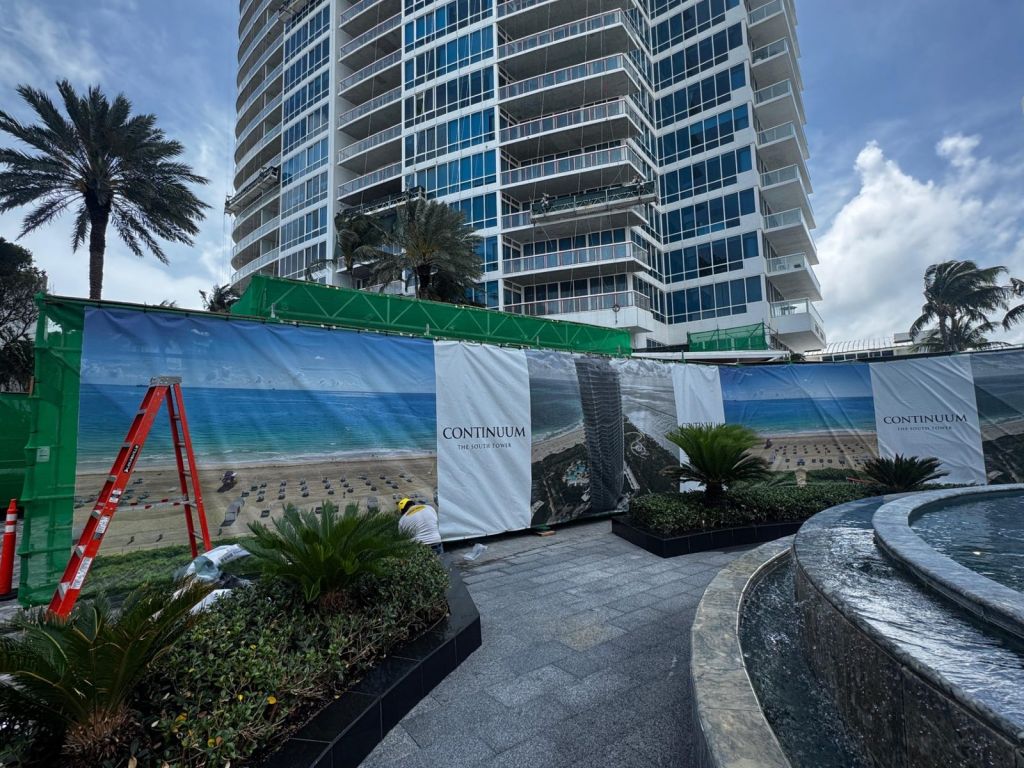 Full-color beach-scene Continuum construction screen in front of a beachfront tower