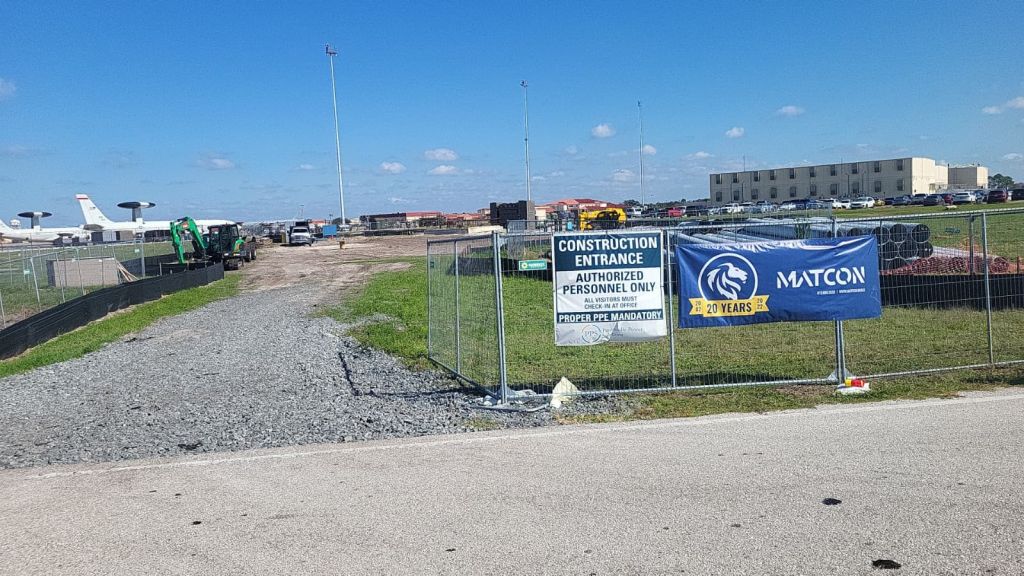 Matcon 20 Years banner beside a construction entrance sign on temporary fence