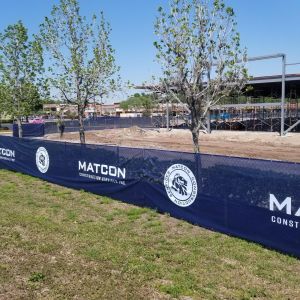 Navy construction screen with white-print Matcon logos around a building site