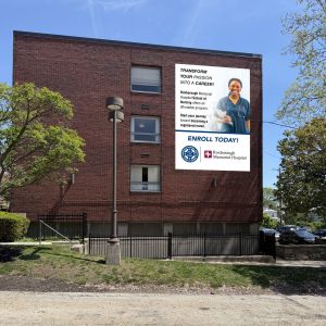 Full color 18 oz vinyl banner for Roxborough Memorial Hospital School of Nursing on a brick building