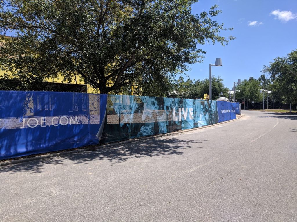 St. Joe printed construction screen wrapping a corner site with a crane lift behind